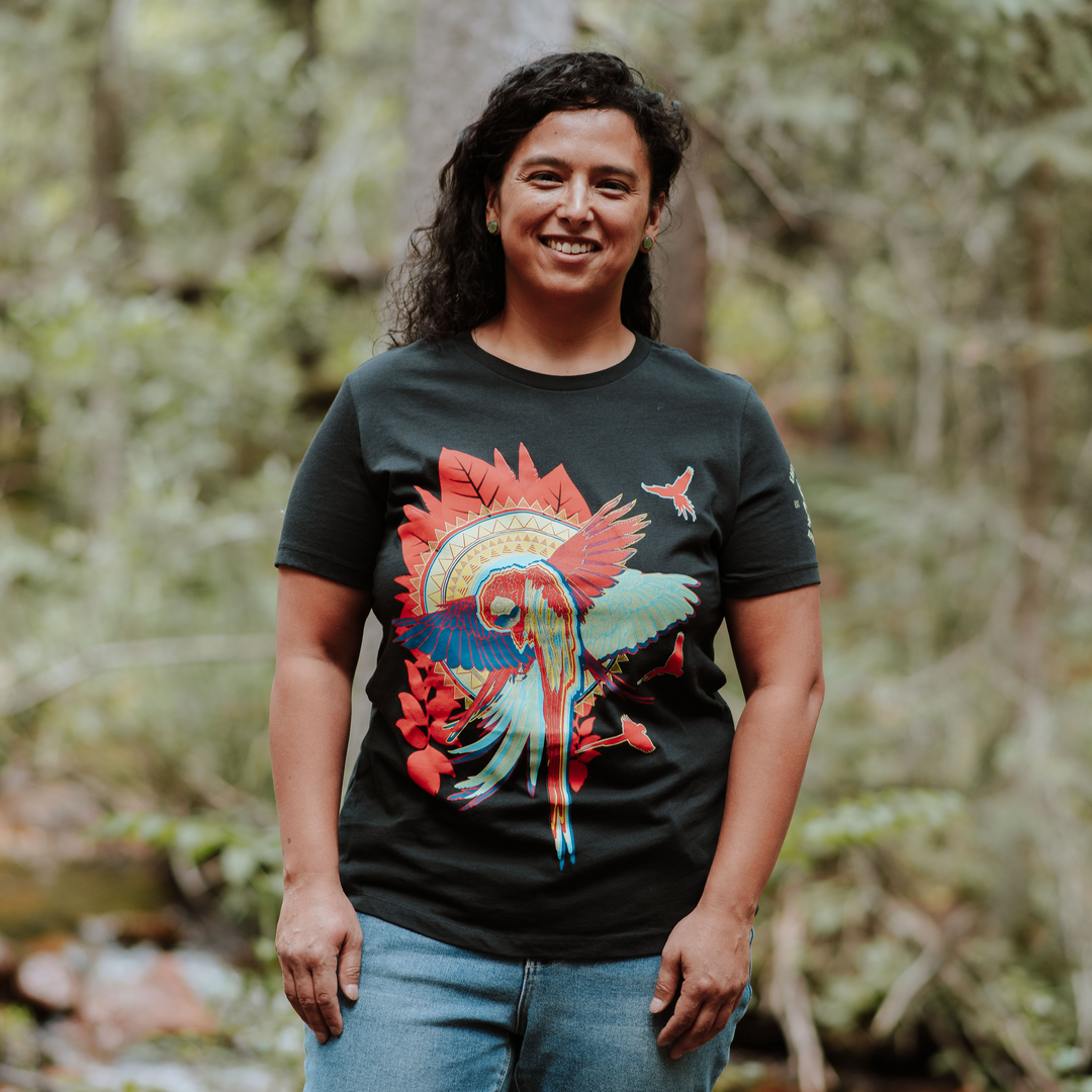 Woman wearing a black t-shirt with a colorful parrot design in a forest setting