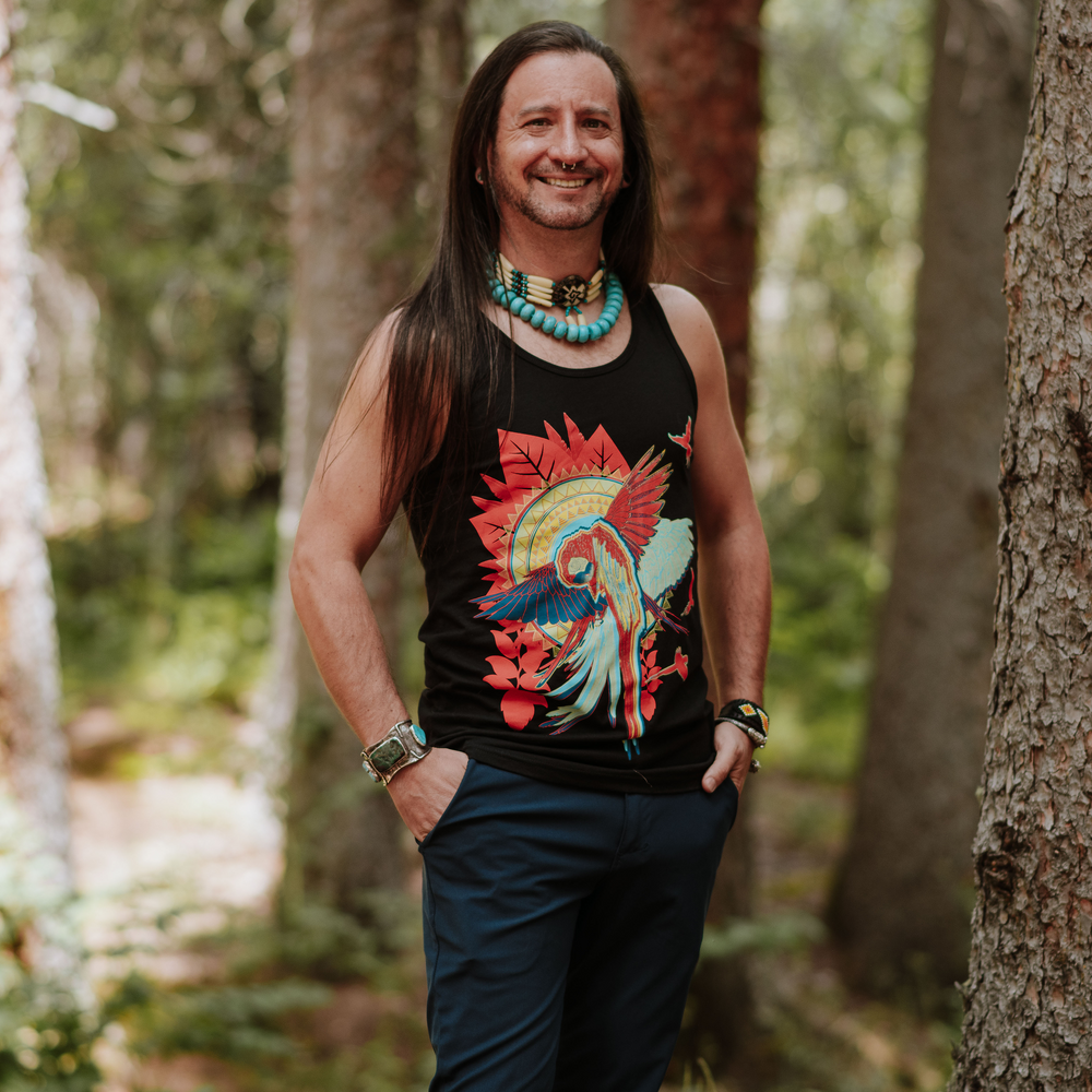 Non-binary person wearing a tank top with a colorful parrot design in a forest setting