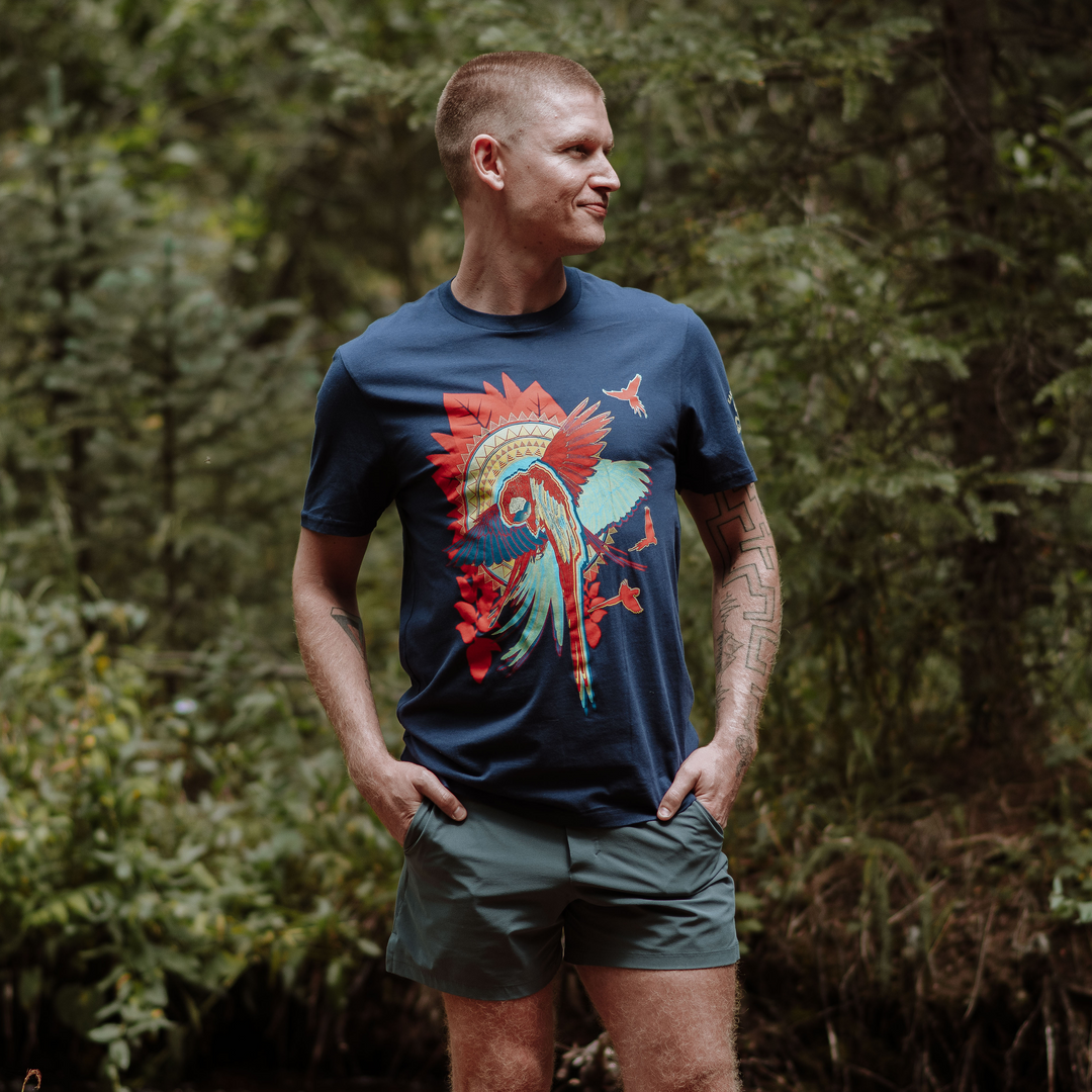 Man wearing a blue t-shirt with a colorful graphic design in a forest setting