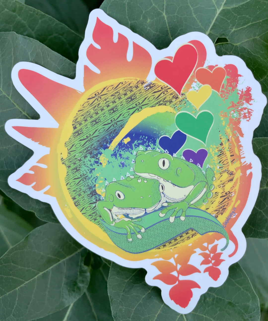 Colorful sticker with frogs, hearts, and a rainbow on a leaf background