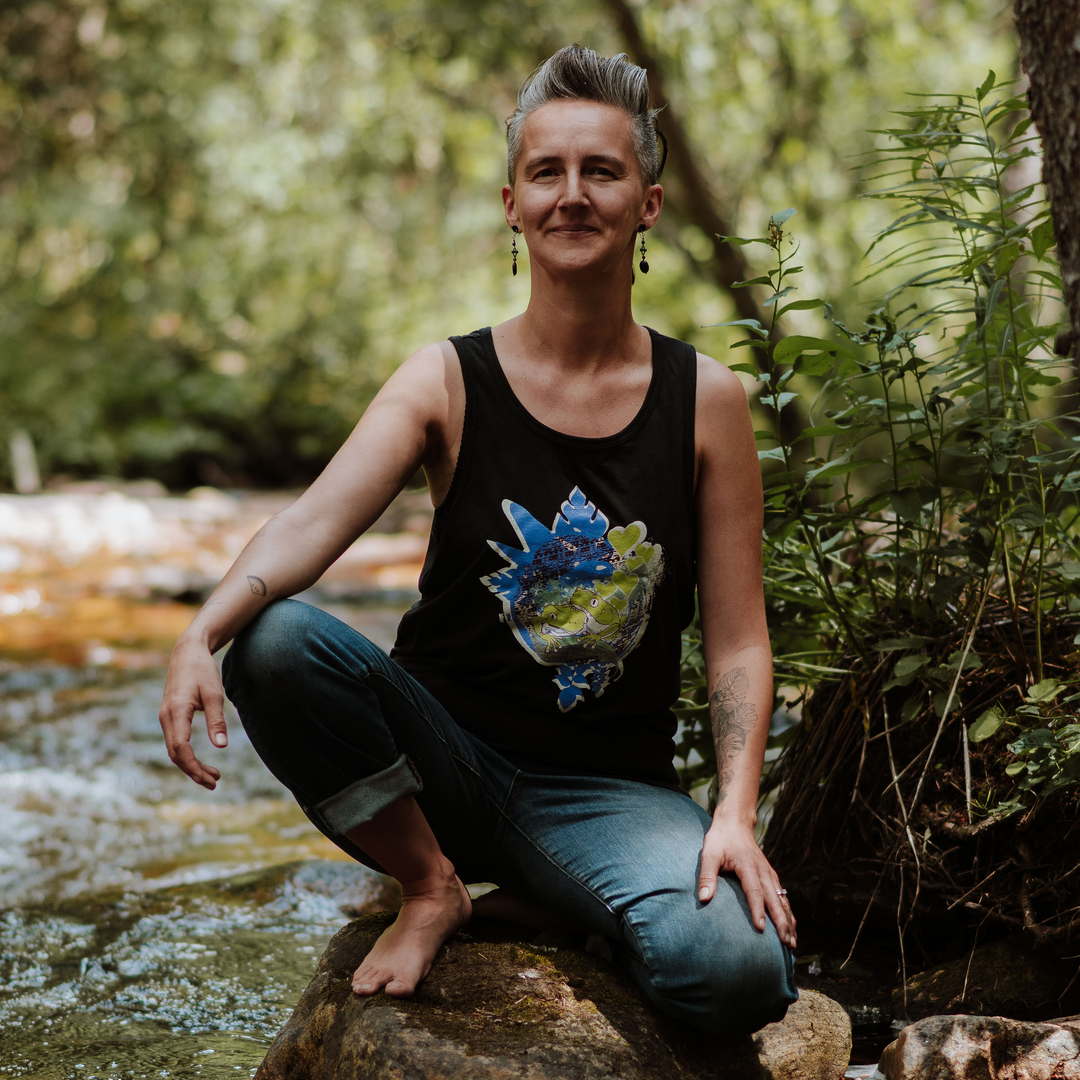 Woman sitting on a rock by a stream with nature in the background