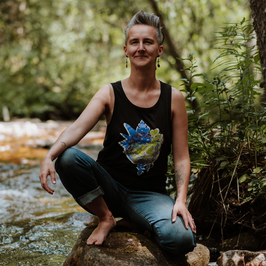Woman sitting on a rock by a stream with nature in the background