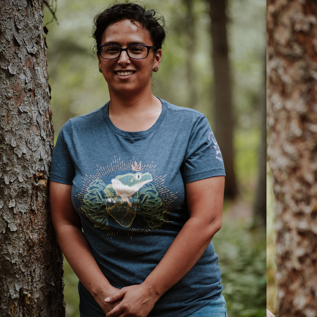 Woman wearing a blue t-shirt with a frog graphic in a forest setting