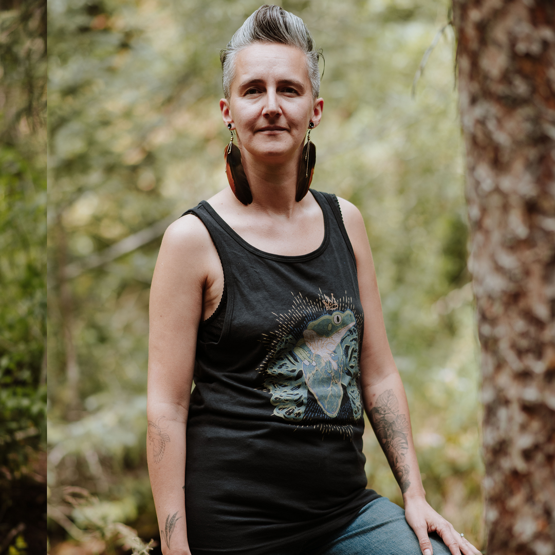 Person wearing a black tank top with a frog design in a forest setting