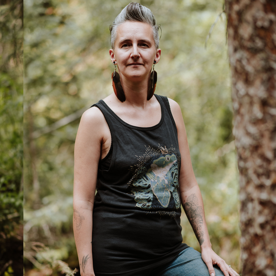 Person wearing a black tank top with a frog design in a forest setting