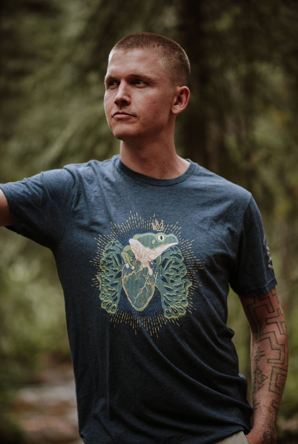 Man wearing a blue t-shirt with a graphic design in a forest setting